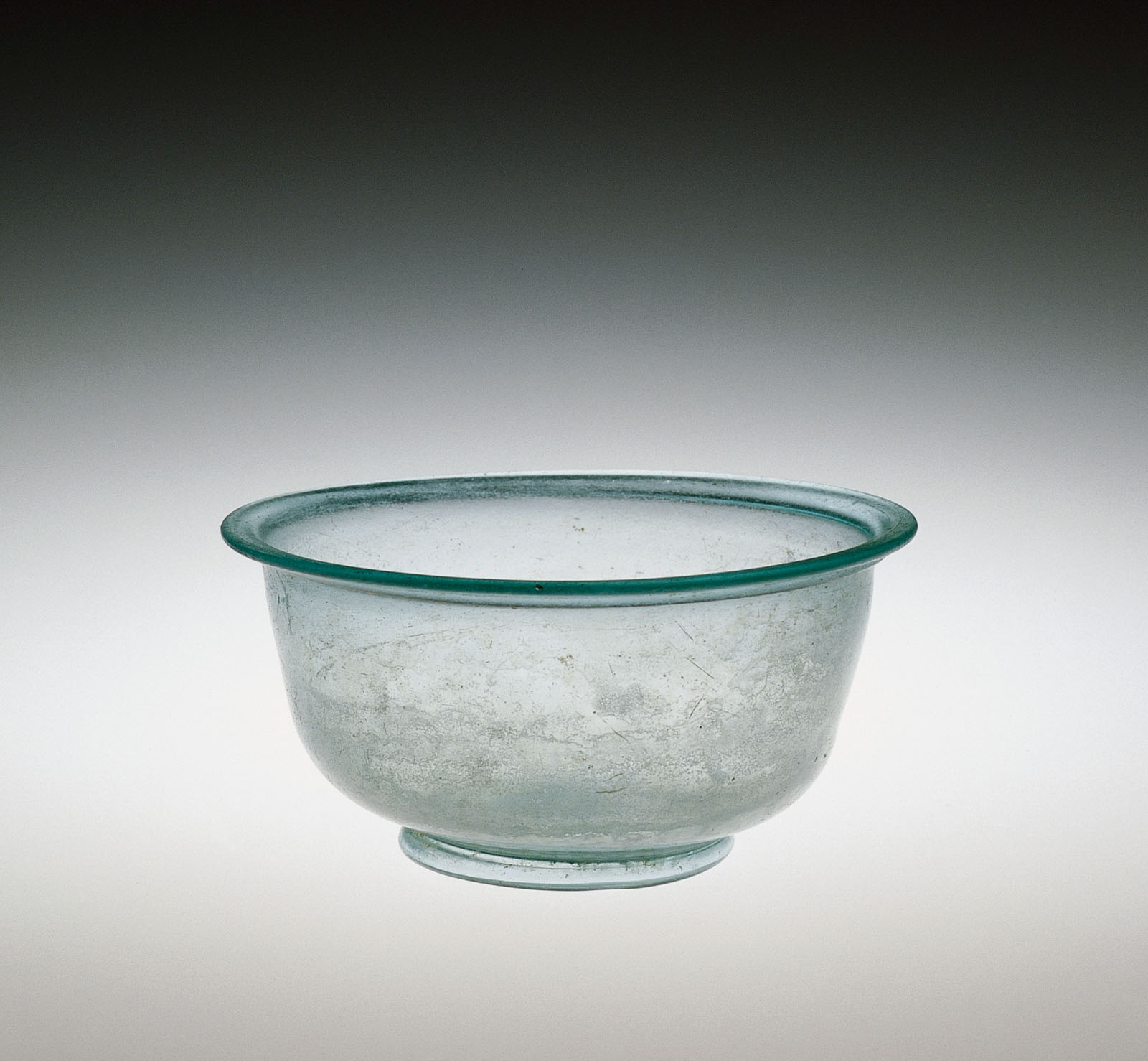 Unadorned, transparent glass bowl with rim and foot, with a slight blue-green tint