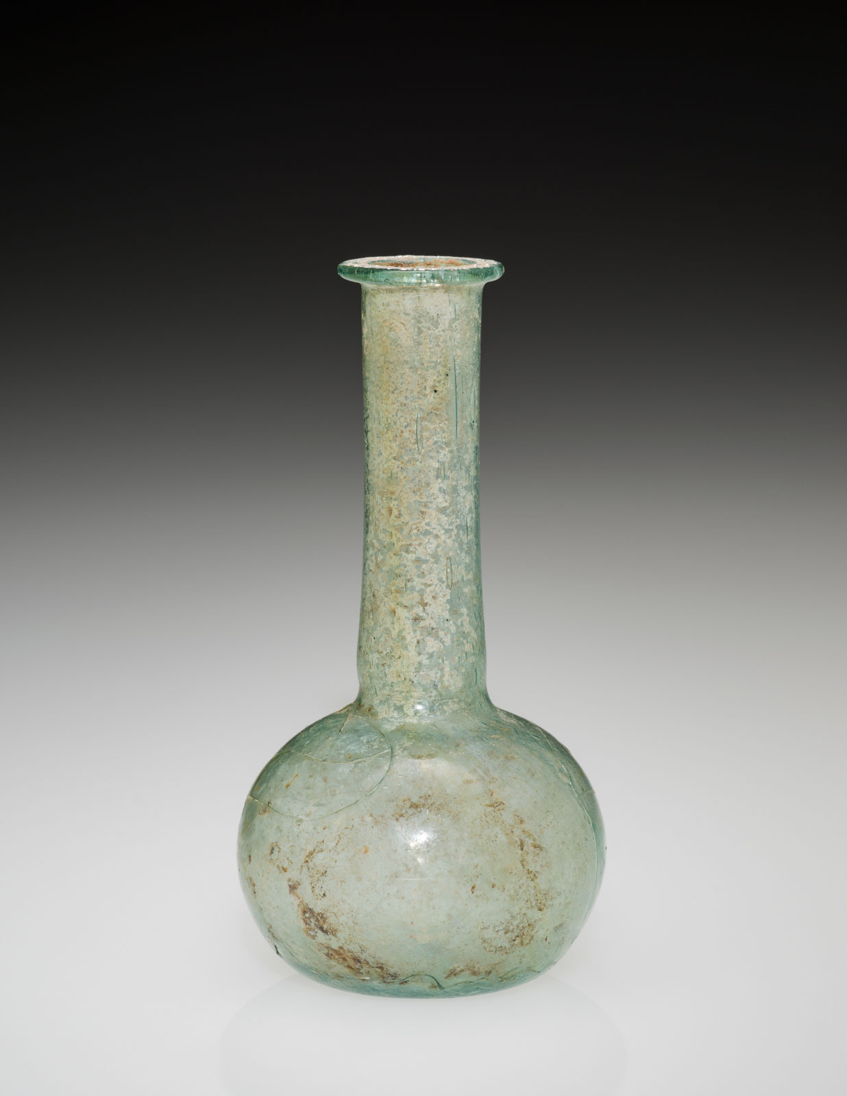 Unadorned, elongated glass vase with a bulbous base and a narrow, straight neck, showing signs of aging