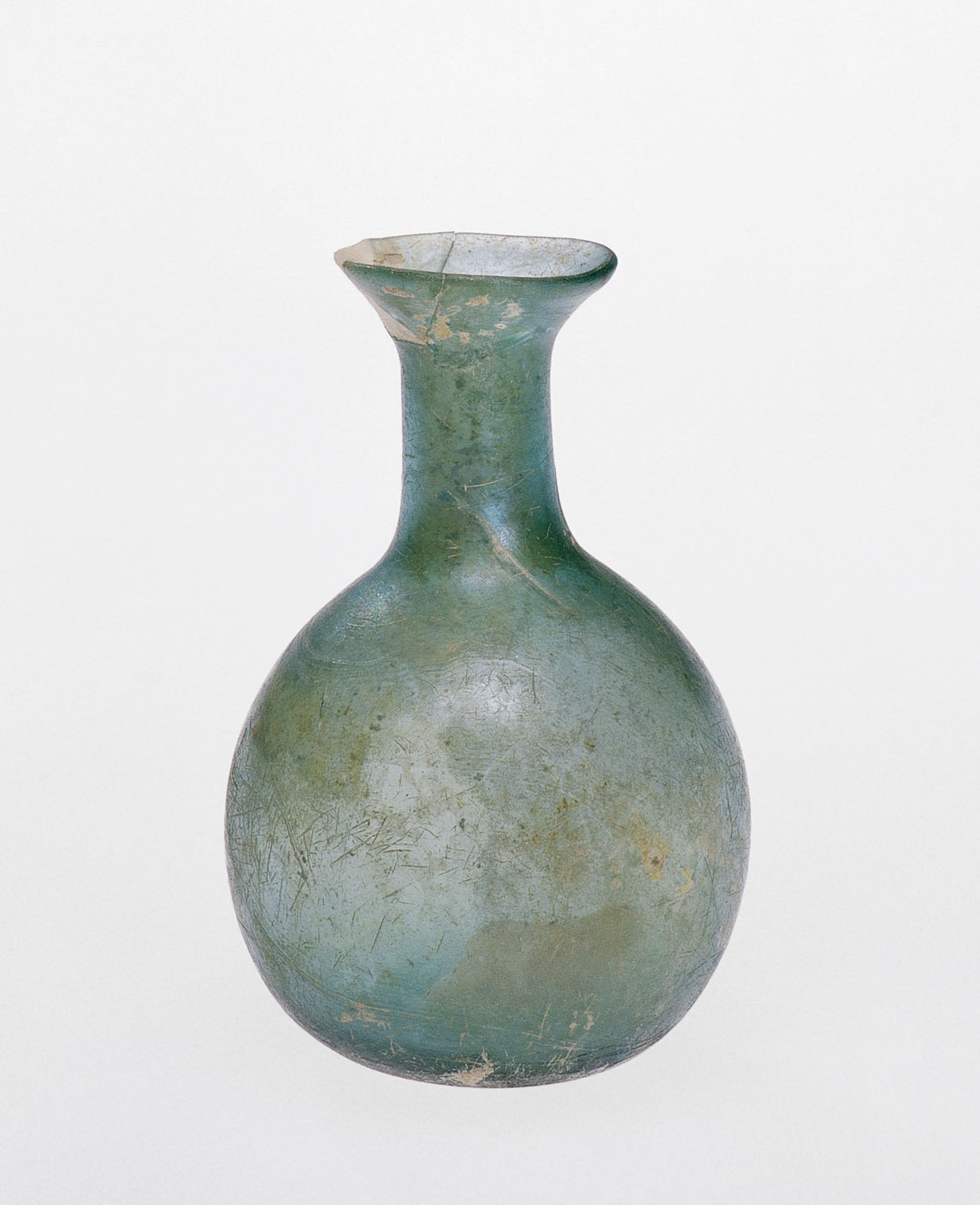 Unadorned pale blue-green glass bottle with a wide, spherical body and a short, tapered neck, showing weathering