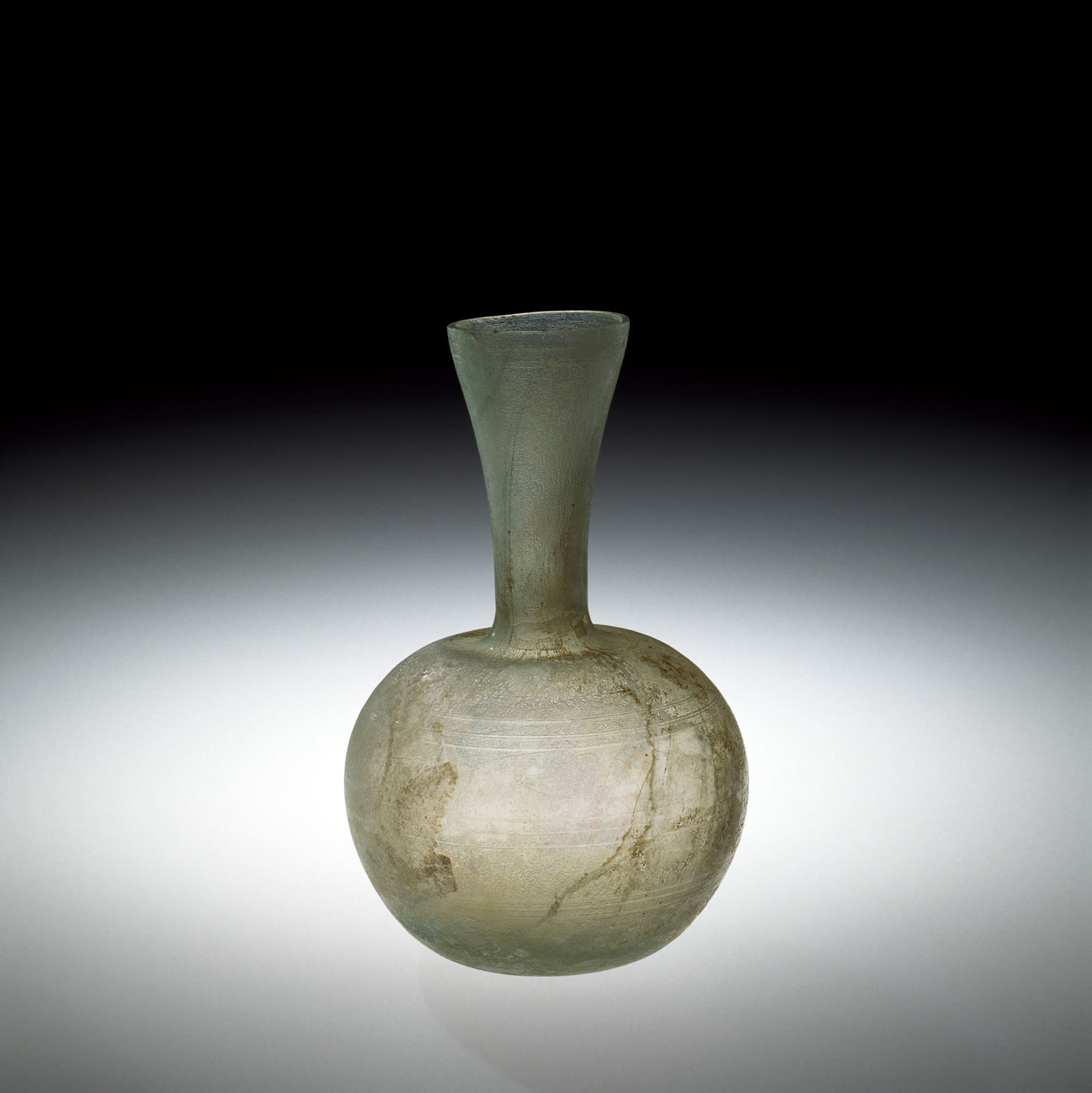 Transparent glass vase with a bulbous base and tapered neck, showing signs of age