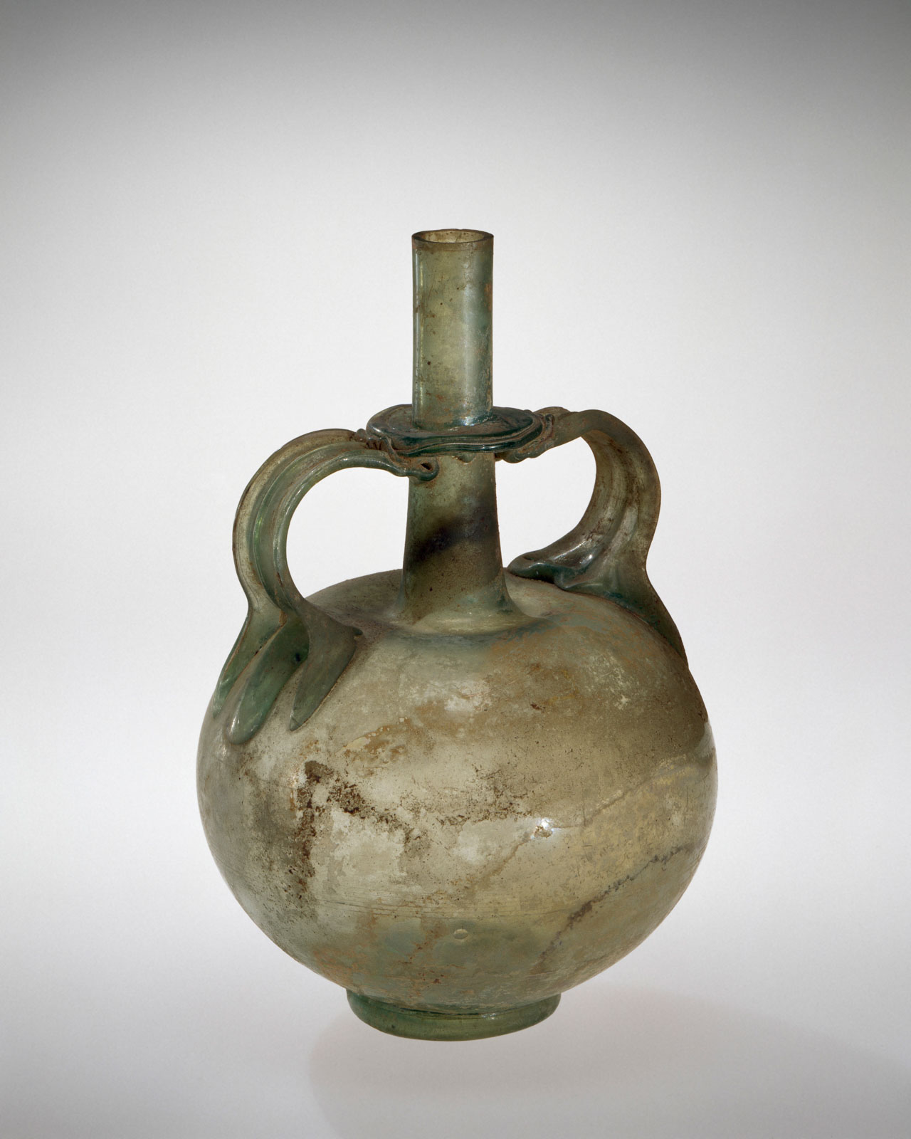 Green glass vessel, spherical with two opposing flat handles, featuring a narrow, cylindrical spout