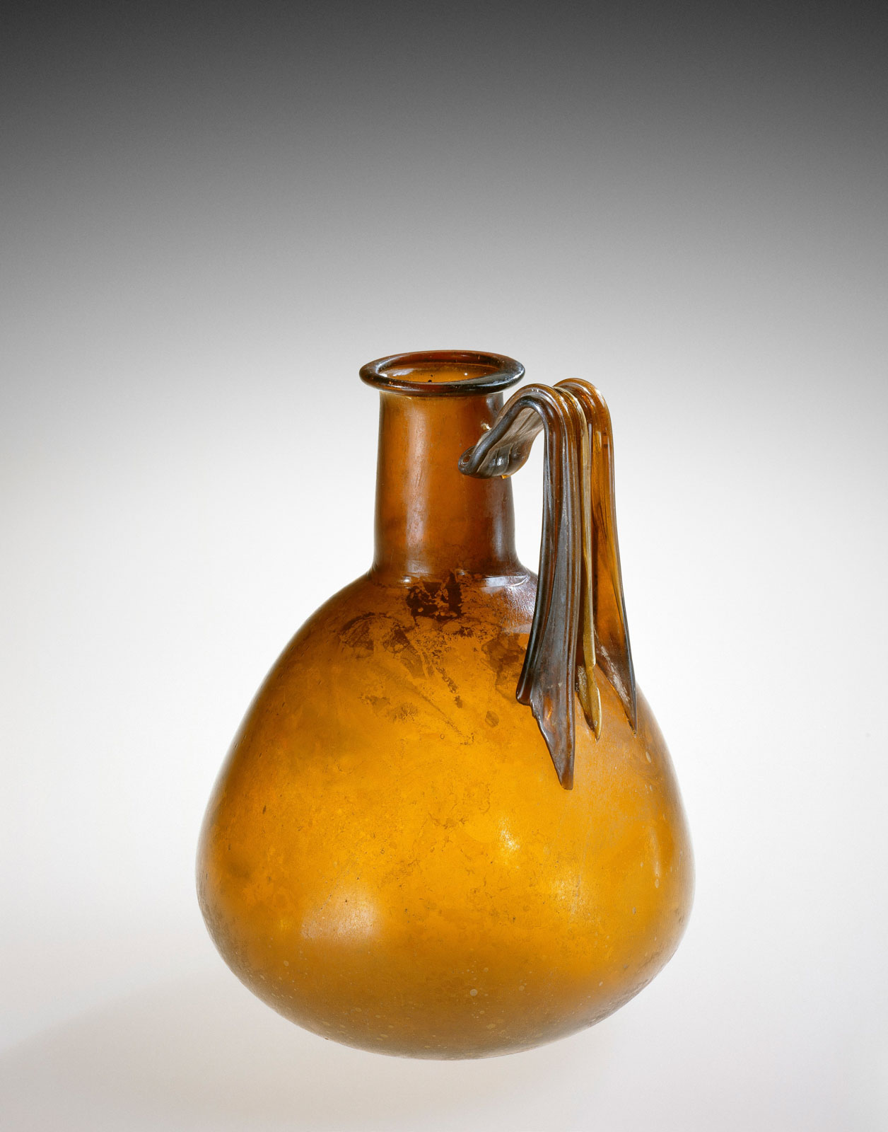 Amber-colored glass vessel with a bulbous body , short neck, and a single, ornate handle