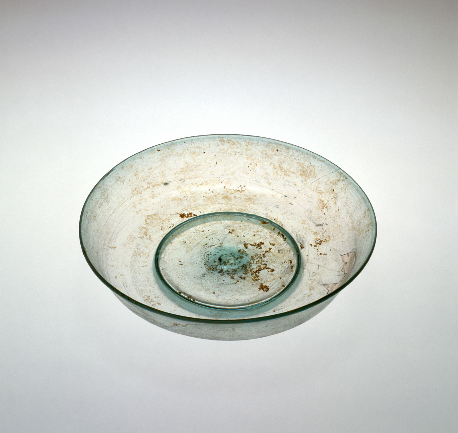 Simple clear, shallow glass bowl showing signs of aging