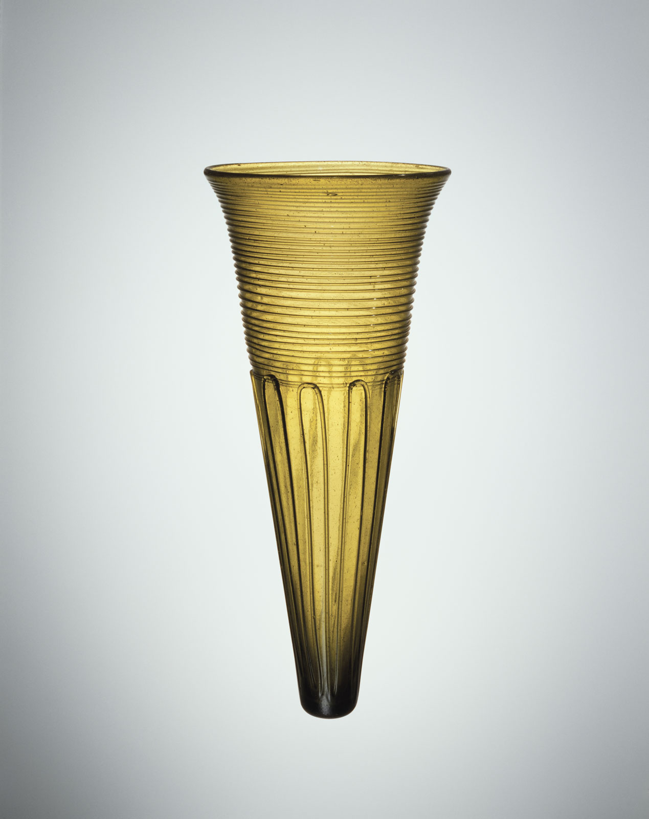 Translucent amber glass cone  tapering to a rounded point, with horiztoal spiral bands at the top and rounded ribbed pattern at the bottom