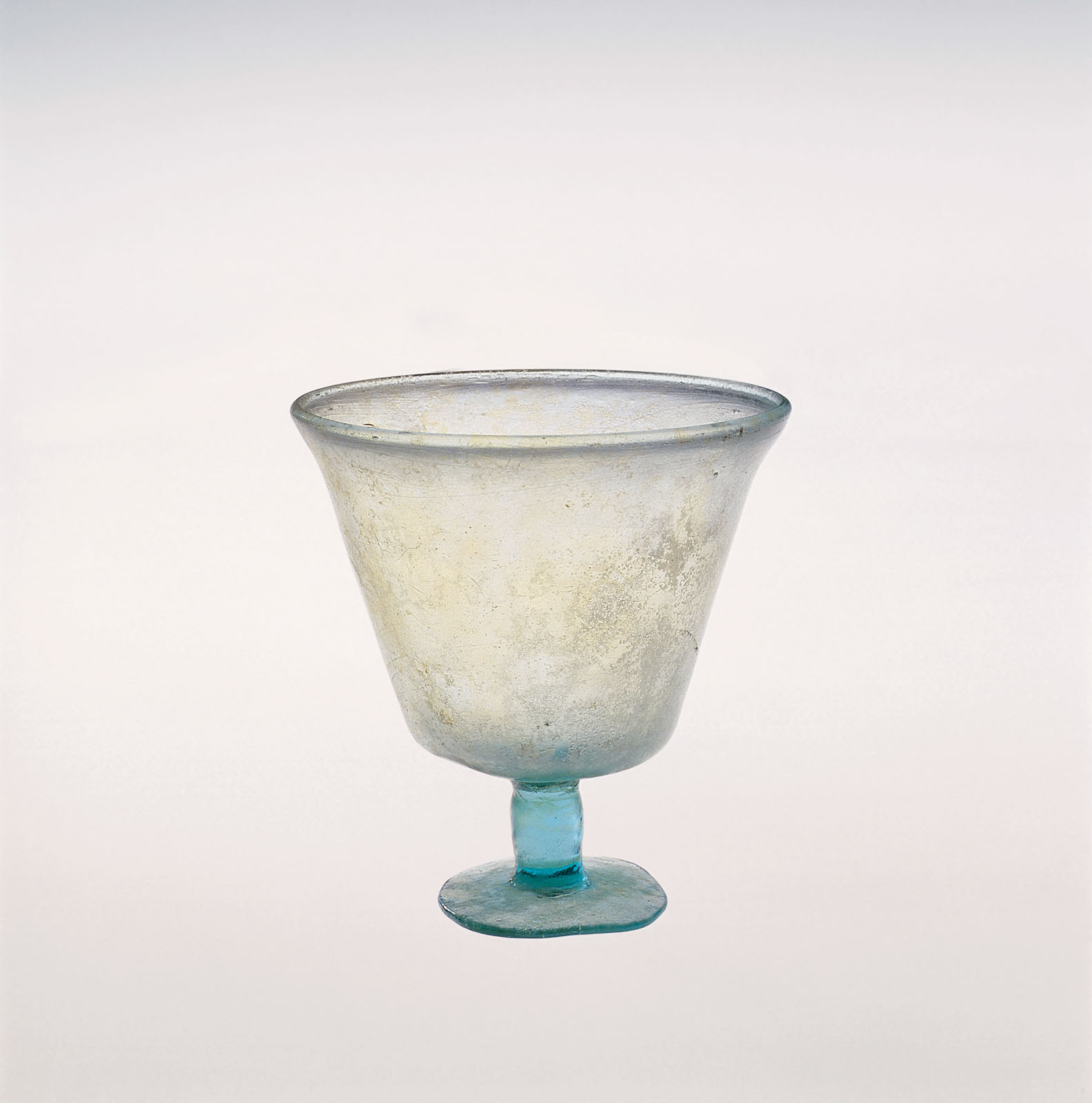 Pale blue glass goblet in a cone shape, with a small uneven foot