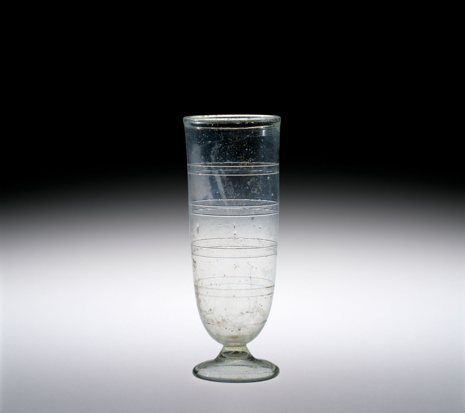 Tall, clear cylindrical glass with horizontal bands and short flared foot